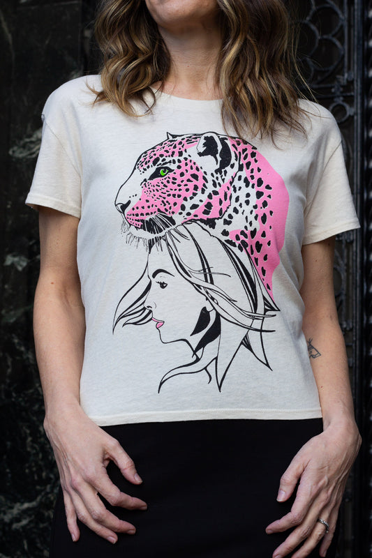 Woman wearing a white t-shirt with a graphic design of a woman's face and a pink leopard on a dark background.