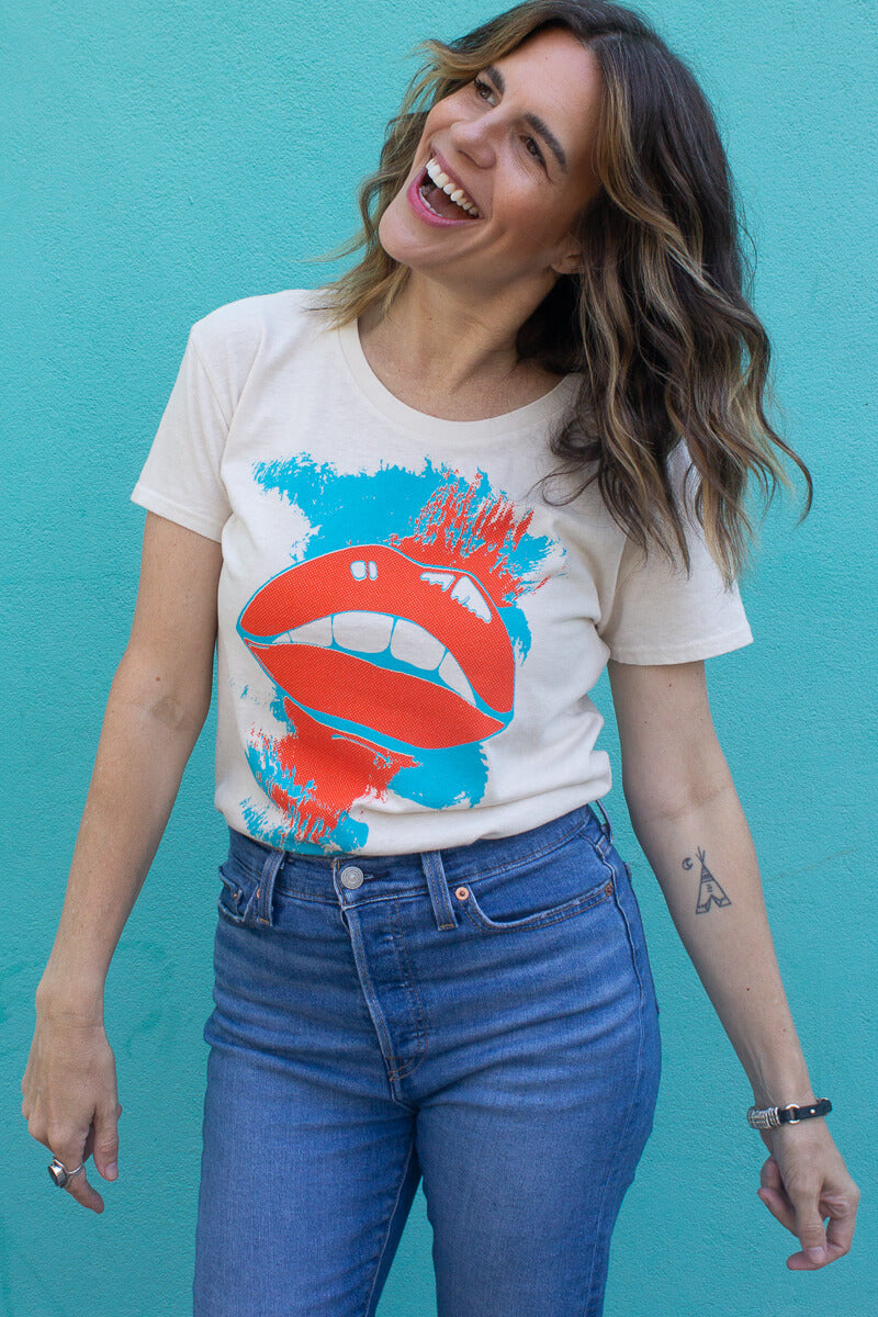 Smiling woman wearing a thread hippie graphic t-shirt with a red and blue design against a blue background.
