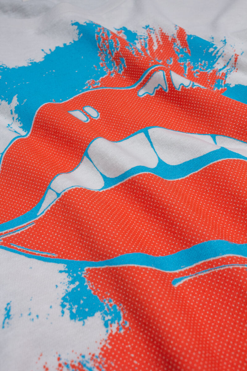 Close-up of a white graphic tee fabric with red and blue pop art pattern.