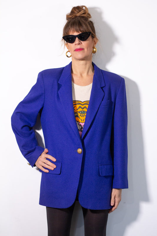 Person wearing a bright blue blazer over a graphic t-shirt on a white background