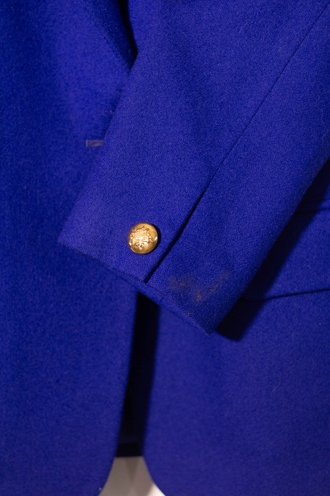Close-up of a blue coat with a gold button