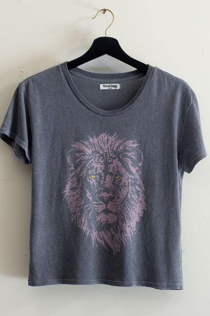 Black women's t-shirt with a lion graphic on a hanger against a white wall.