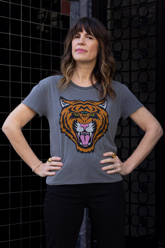Woman wearing a black t-shirt with a tiger graphic design against a dark city background.