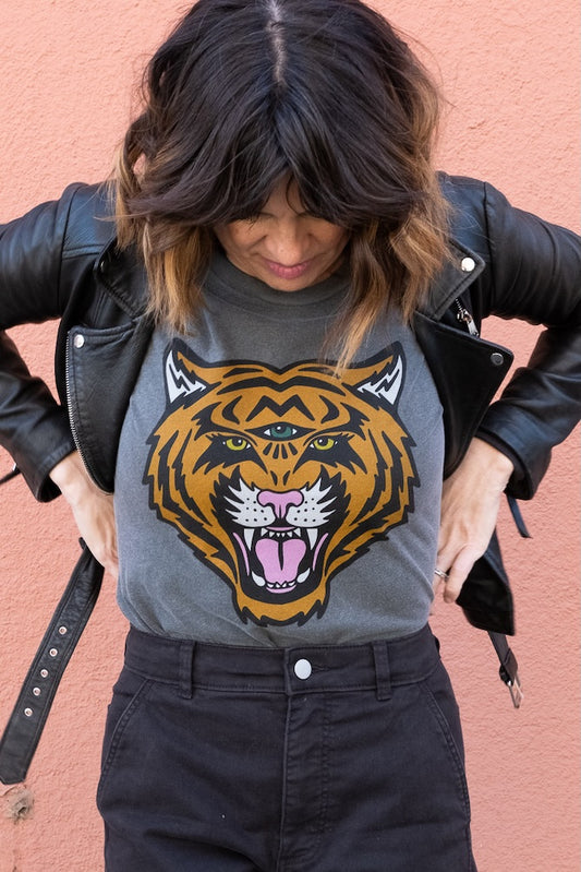 Woman wearing a vintage black t-shirt with a tiger graphic design against a pink background.
