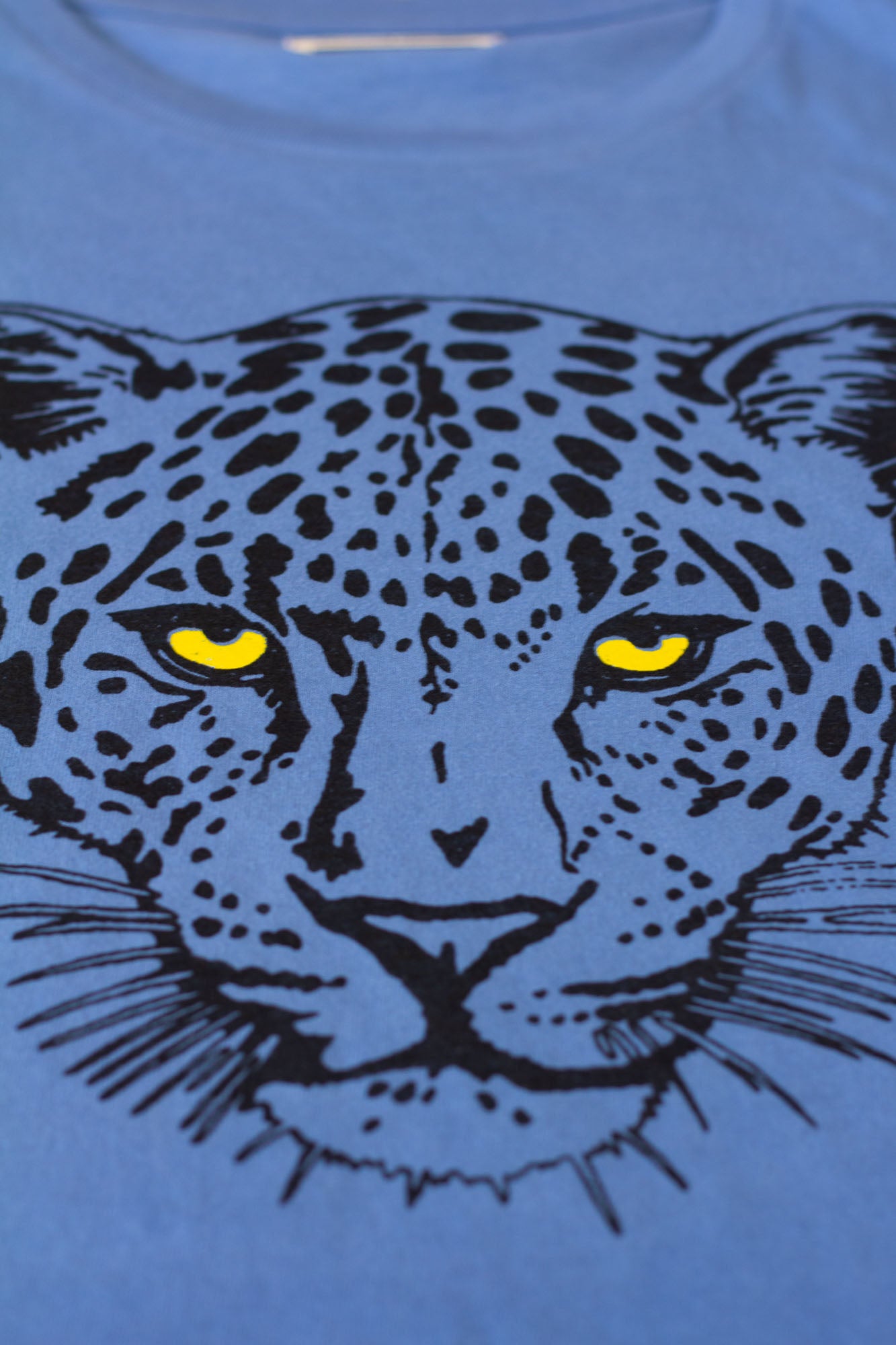 Blue t-shirt with a black leopard graphic and yellow eyes.
