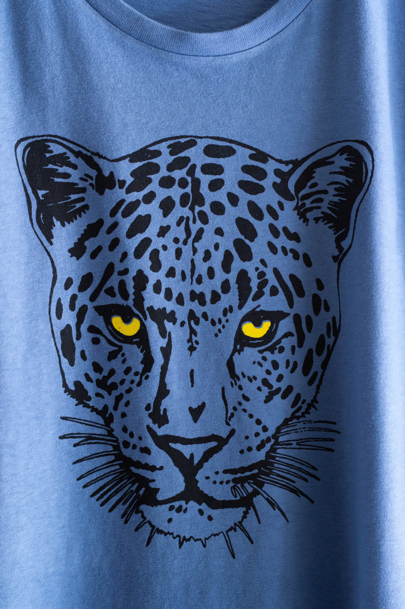 Blue women's t-shirt with a black leopard graphic on a plain background.