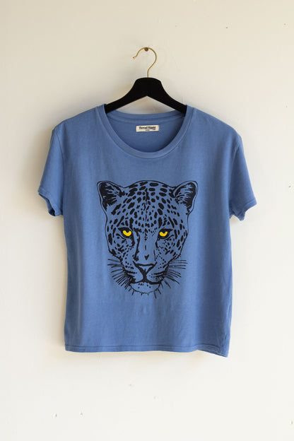 Blue women's t-shirt with a leopard graphic on a hanger against a white background.