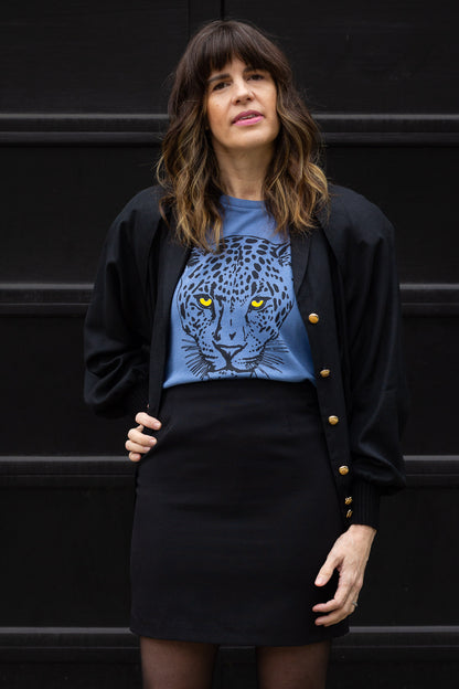 Woman wearing a blue t-shirt with a leopard design against a black background.