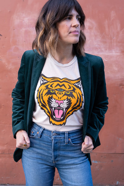 Woman wearing a white tiger graphic design against a red-brown wall.