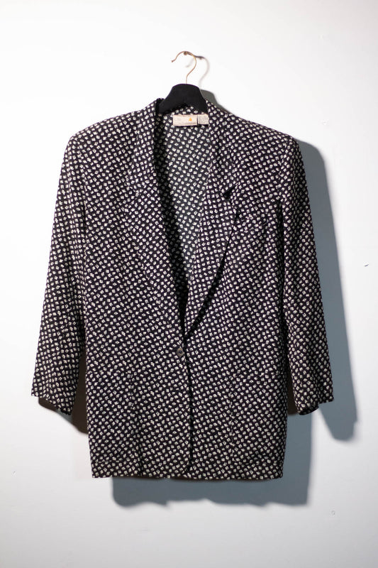 Vintage Liz Claiborne black and white patterned blazer on a hanger against a white background.