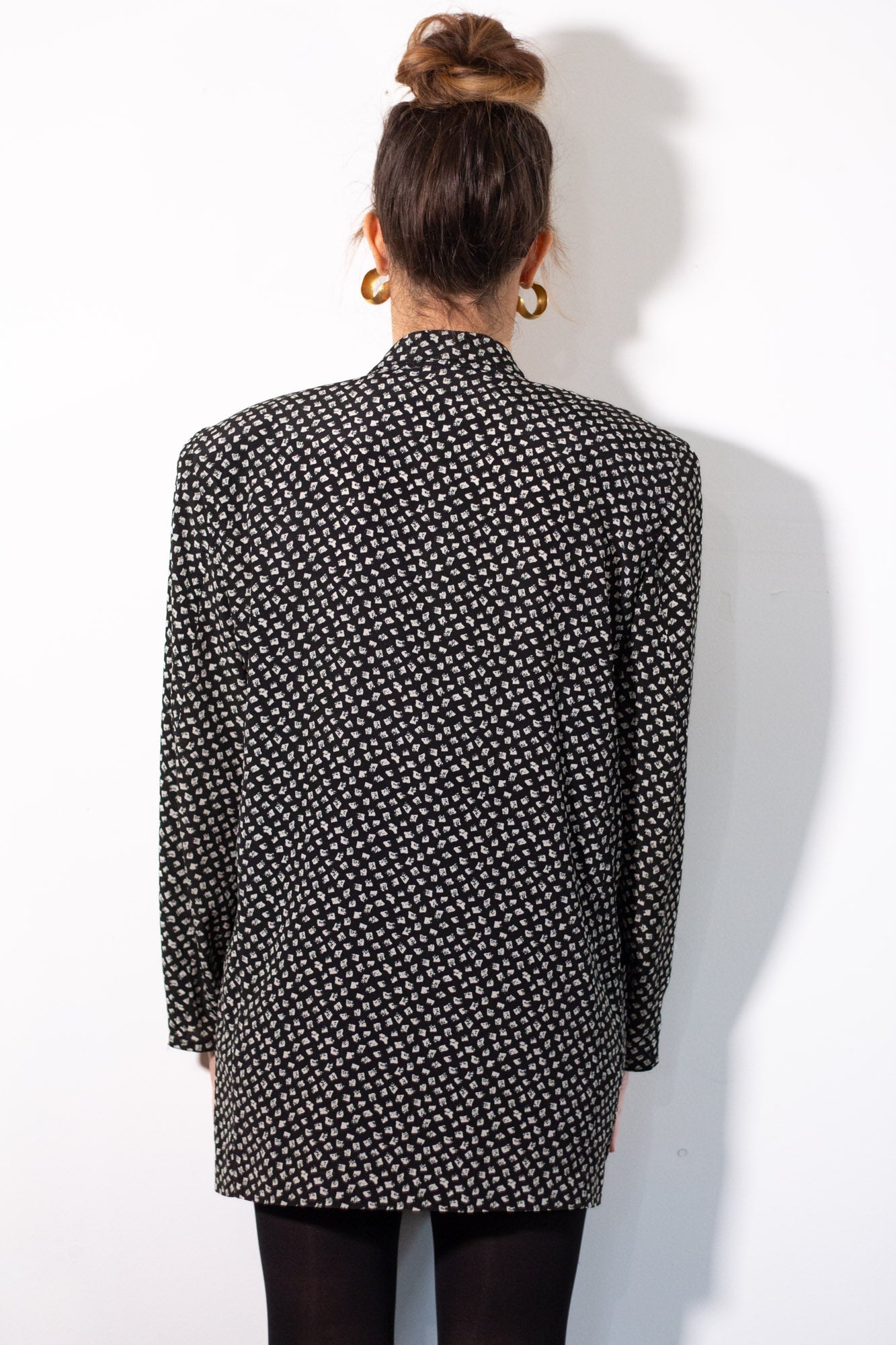Person wearing a black and white patterned shirt against a white background
