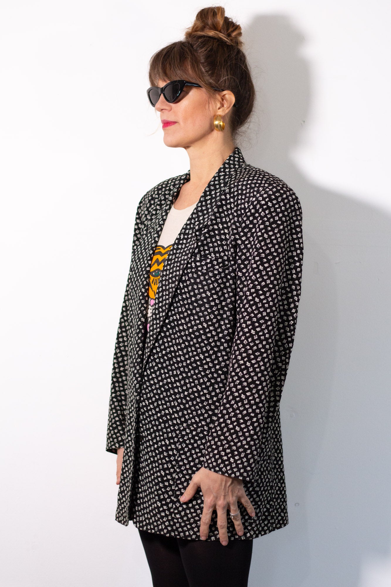 Woman wearing a black and white patterned blazer against a white background