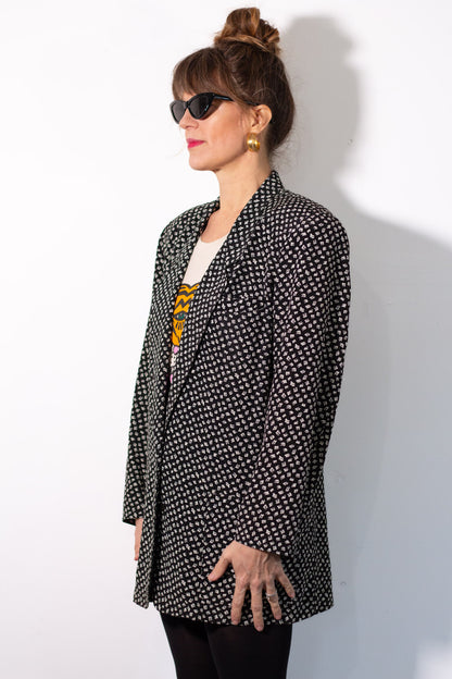 Woman wearing a black and white patterned blazer against a white background