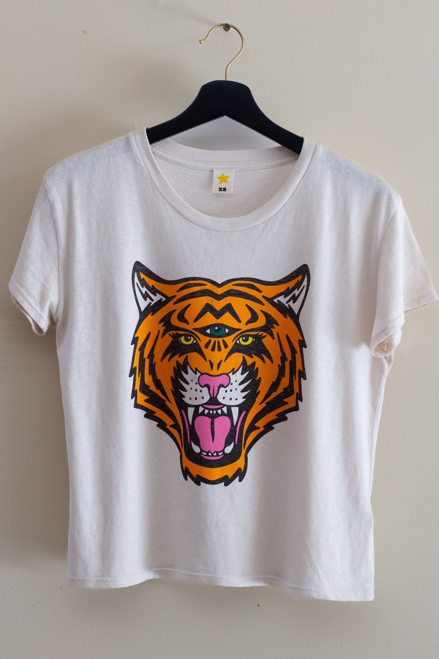 White t-shirt with a tiger graphic on a hanger against a plain background.