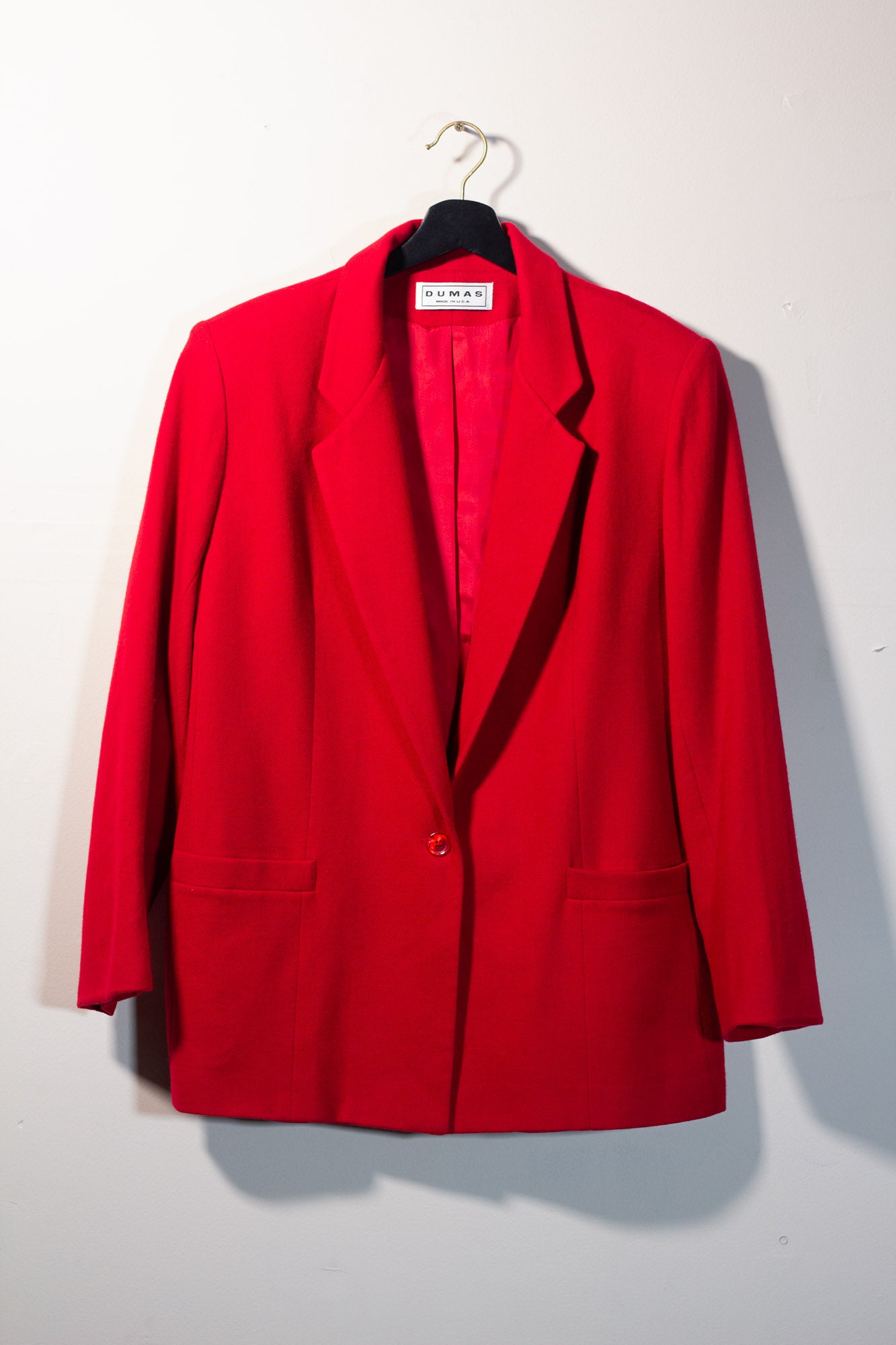 Red blazer on a hanger against a white background