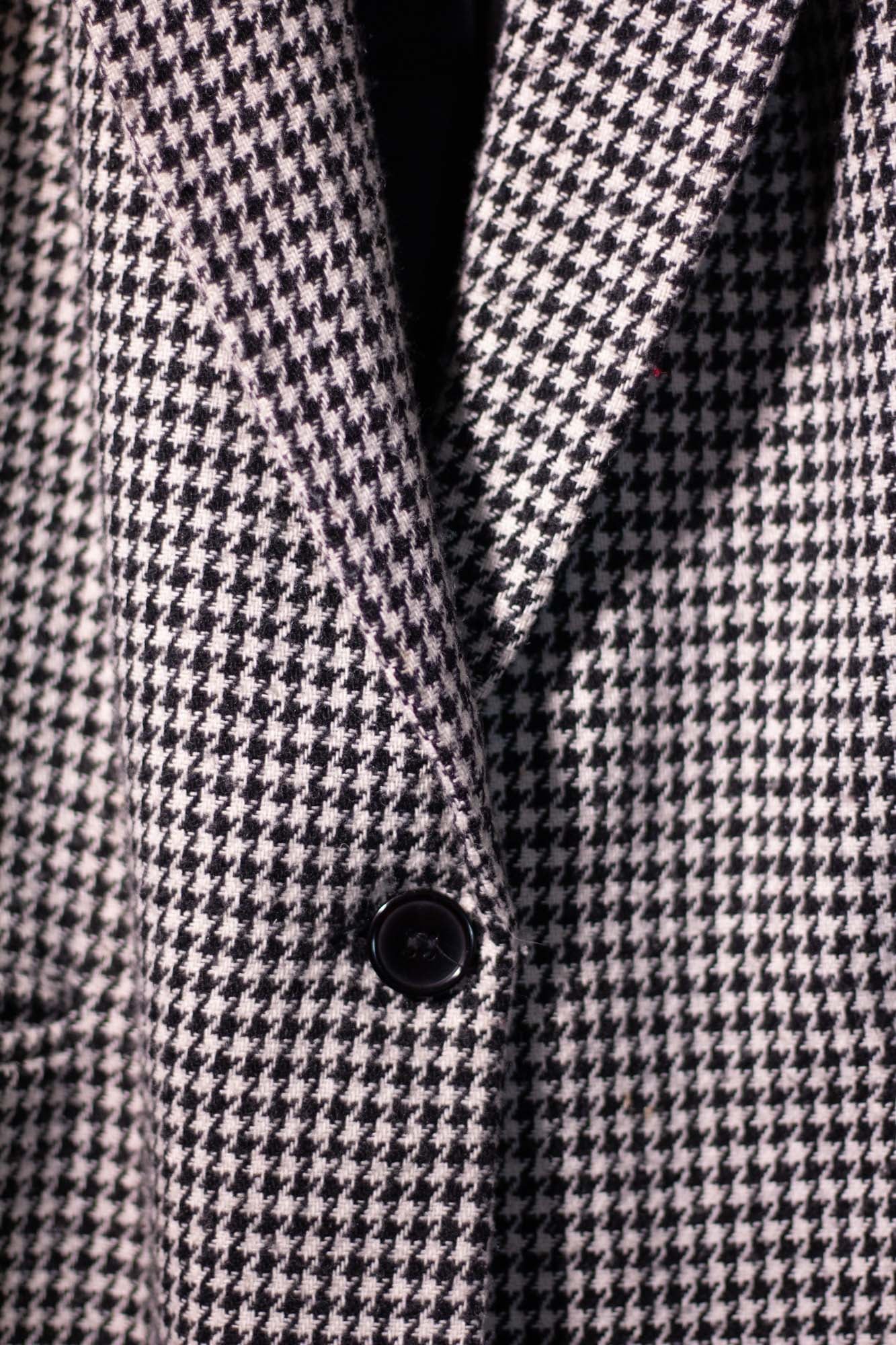 Close-up of a houndstooth patterned coat with a button.