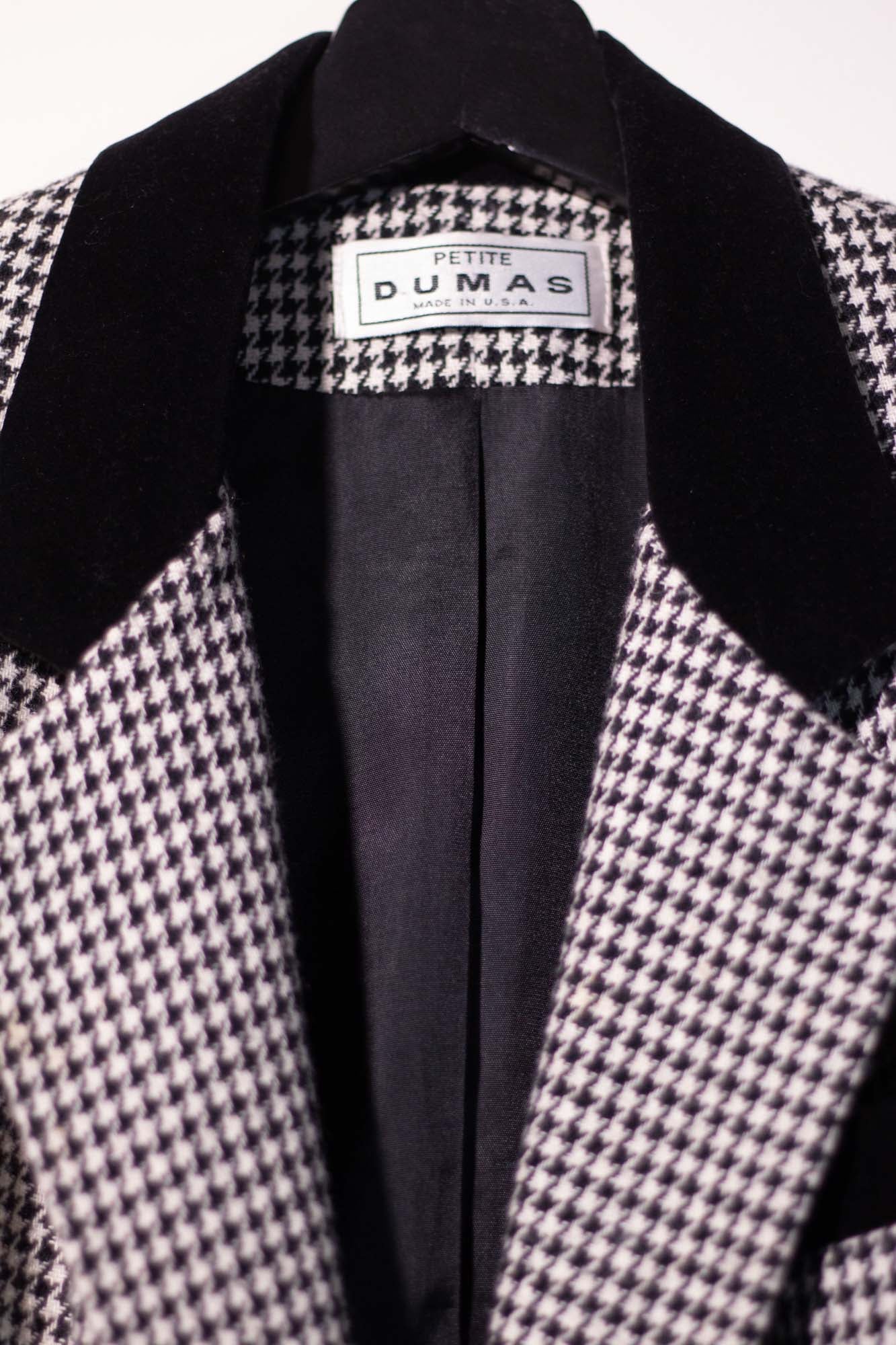 Houndstooth patterned coat with black lapels and visible brand label on a white background