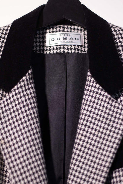 Houndstooth patterned coat with black lapels and visible brand label on a white background
