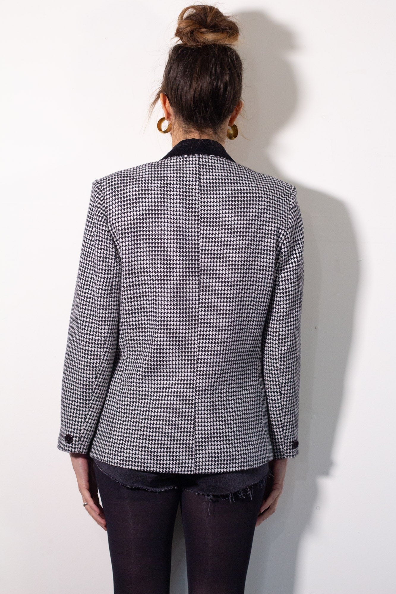 Person wearing a houndstooth patterned blazer against a white background