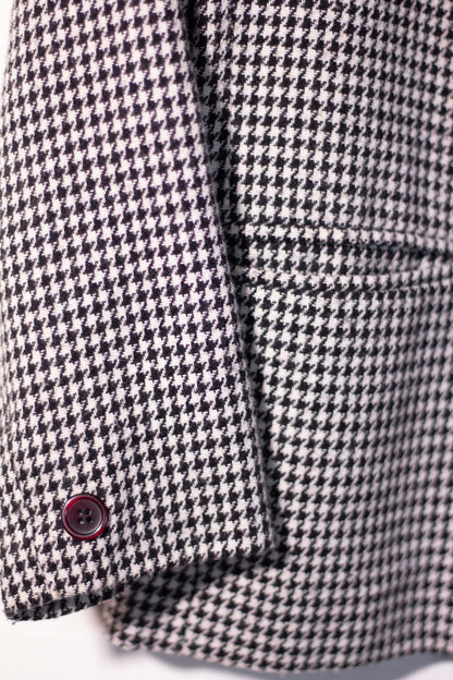 Close-up of a houndstooth patterned coat with a button on a white background