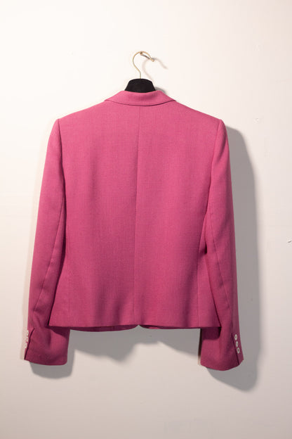 Pink blazer on a hanger against a white wall