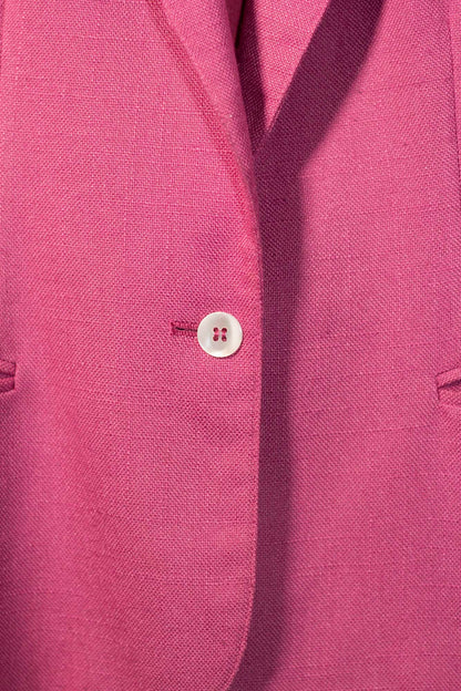 Close-up of a pink blazer with a button on a matching fabric background
