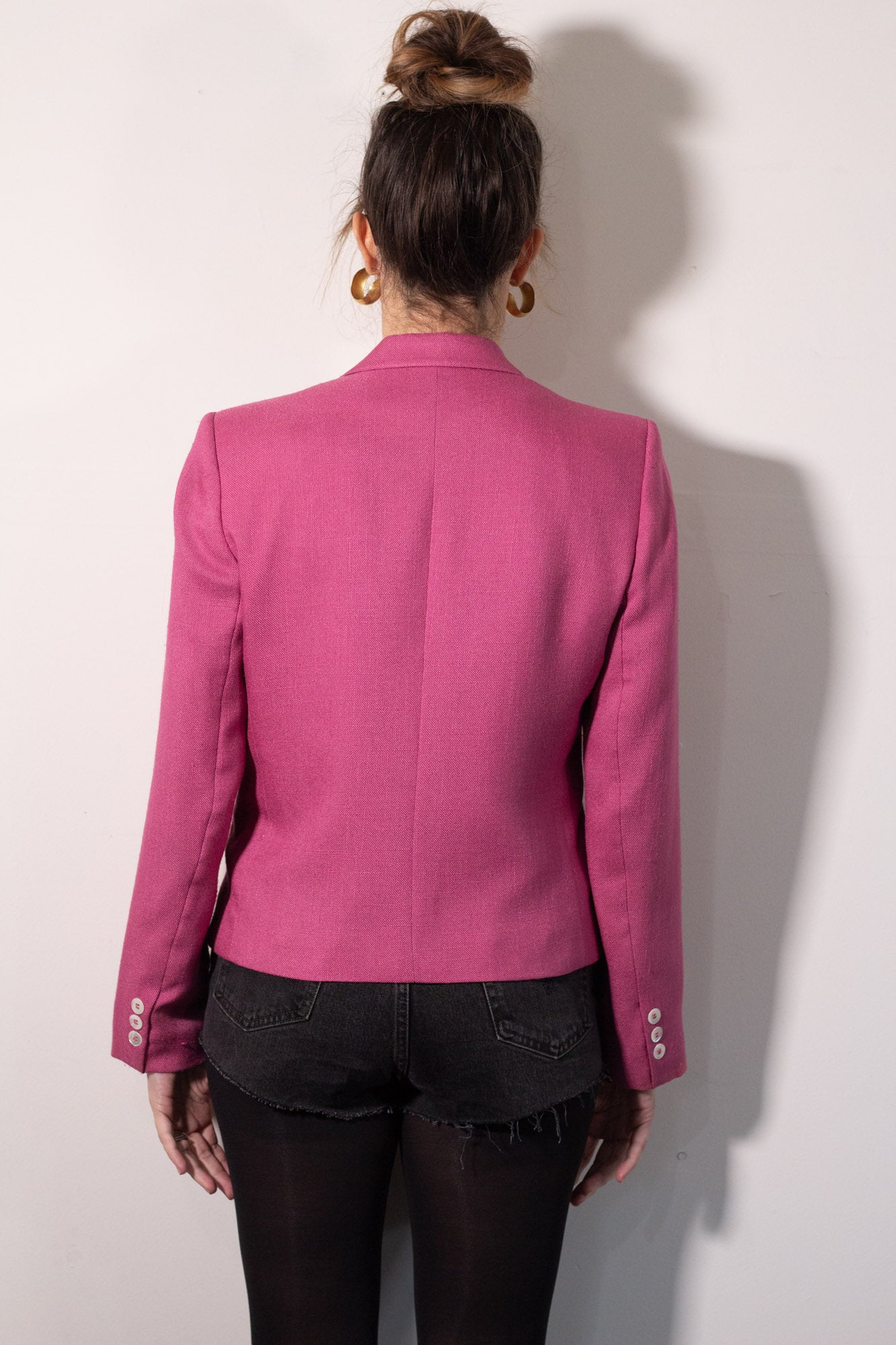 Person wearing a pink blazer from behind on a white background