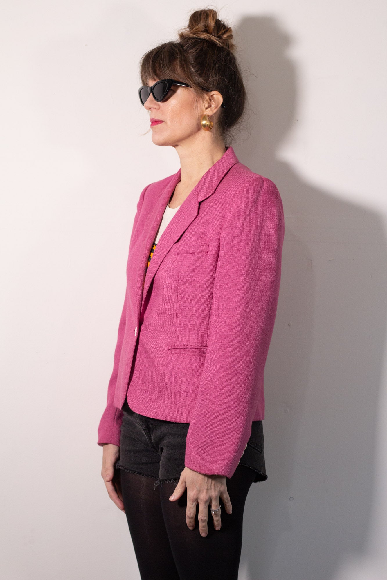 Woman wearing a pink blazer against a white wall