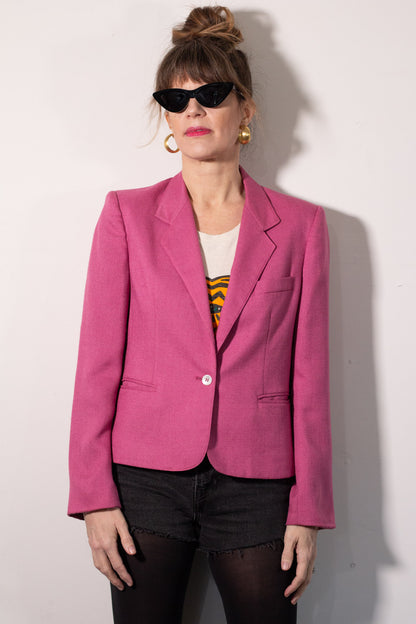 Person wearing a pink blazer against a white background