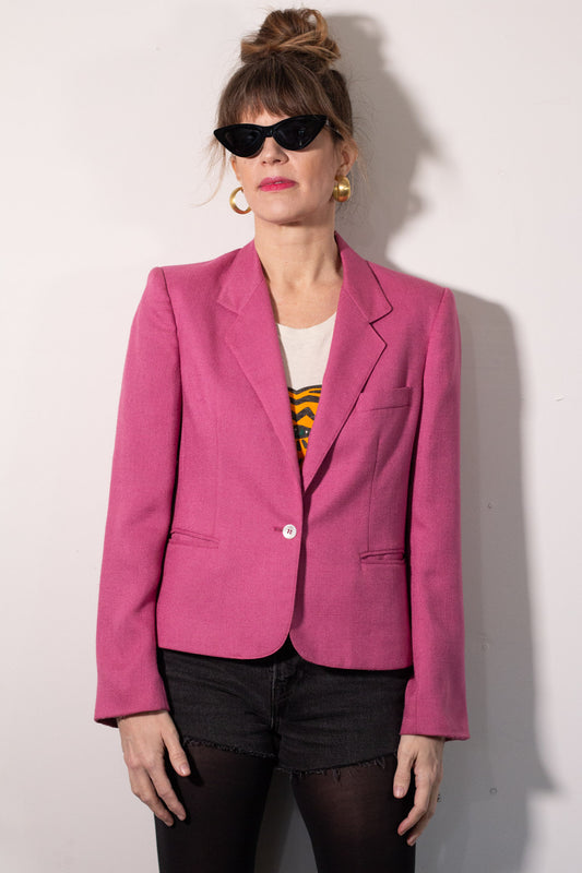 Person wearing a pink blazer against a white background