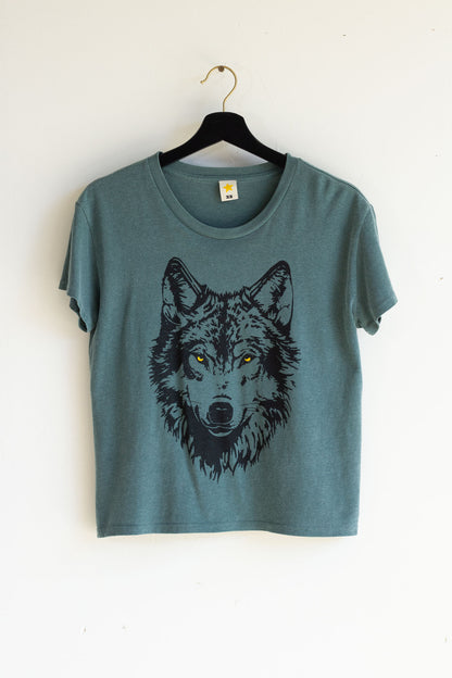Green women's t-shirt with a wolf graphic on a hanger against a white background.