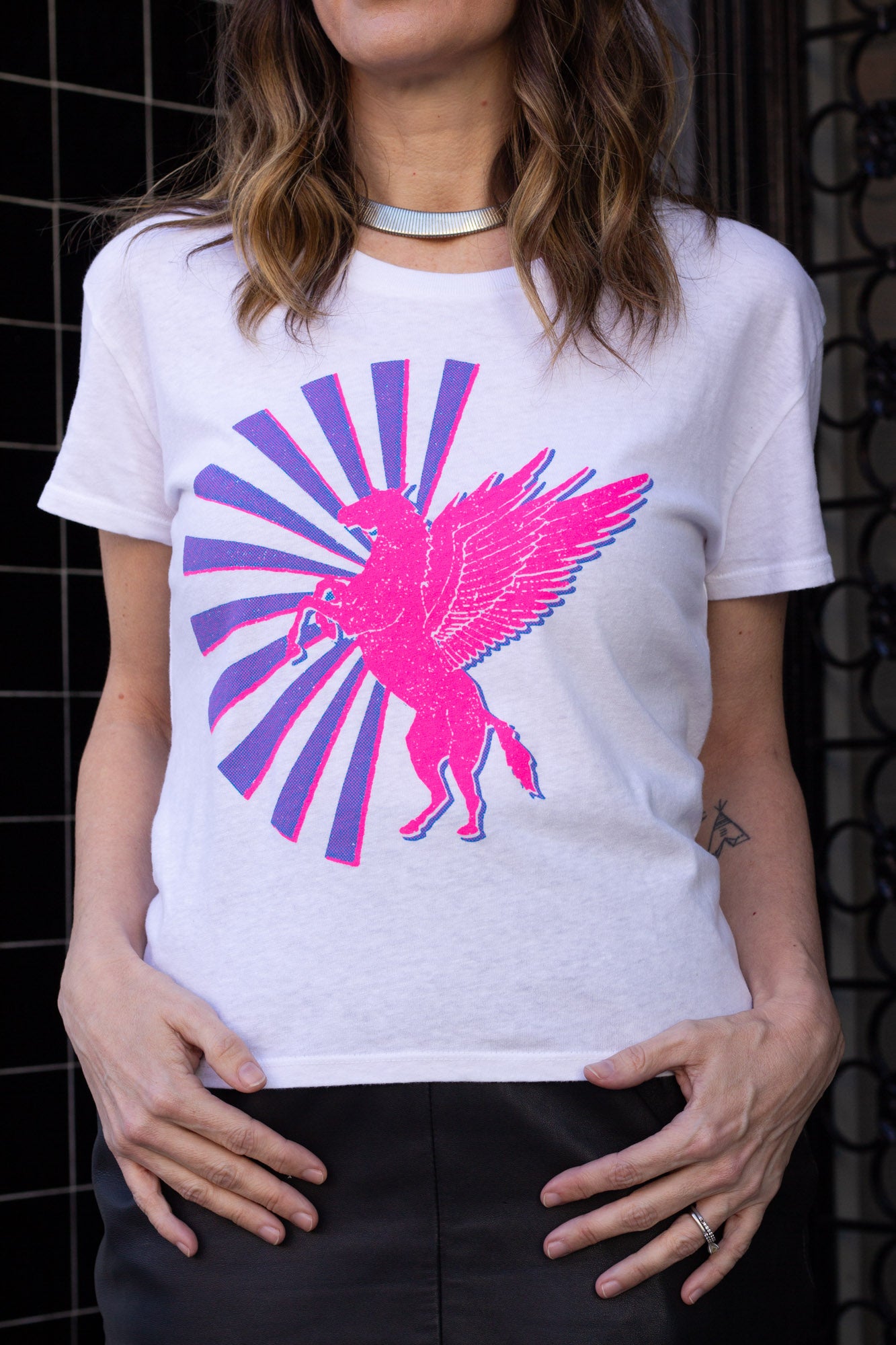 Woman wearing a white t-shirt with a pink and purple horse graphic design.