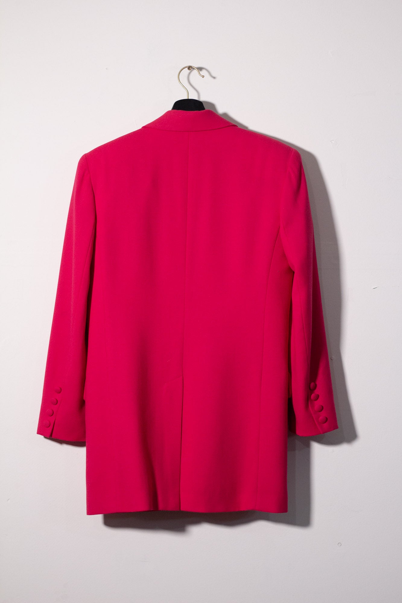 Pink blazer on a hanger against a white background
