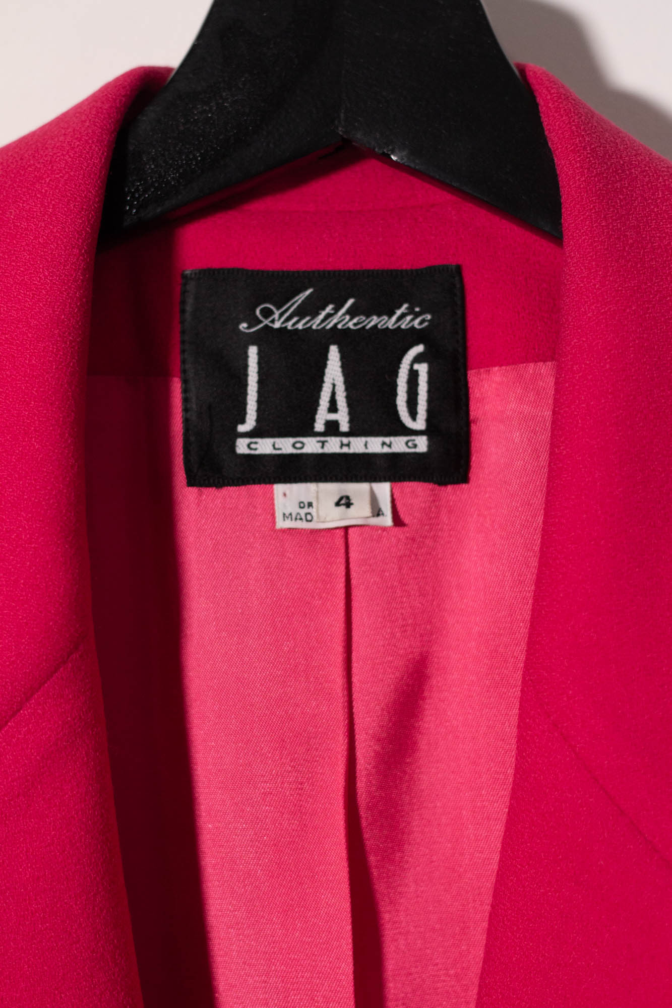 Close-up of a pink garment with an 'Authentic JAG Clothing' label on a black background