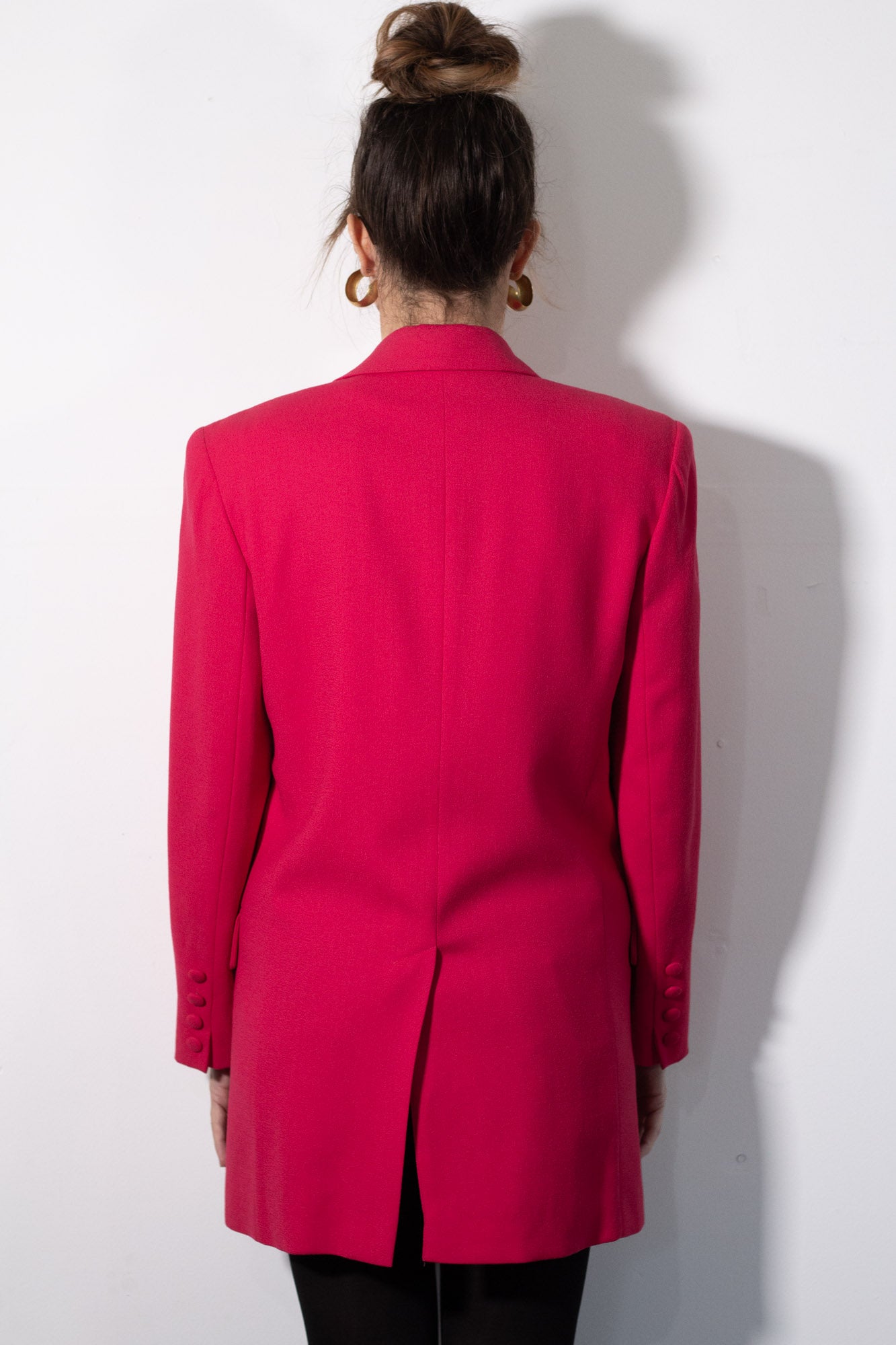 Person wearing a bright pink blazer against a white background