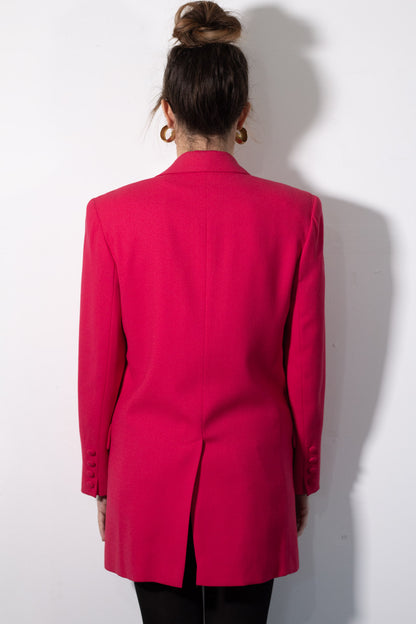 Person wearing a bright pink blazer against a white background