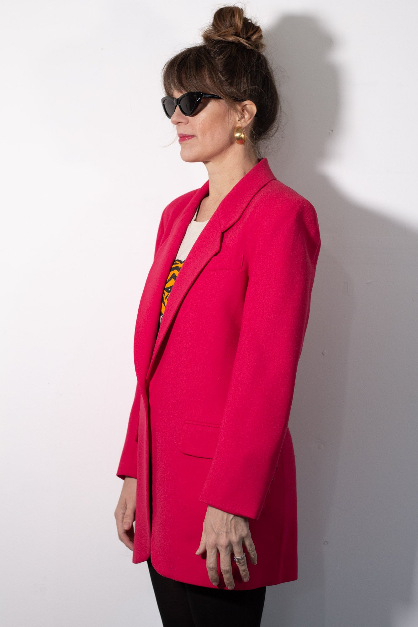 Woman wearing a bright pink blazer against a white background