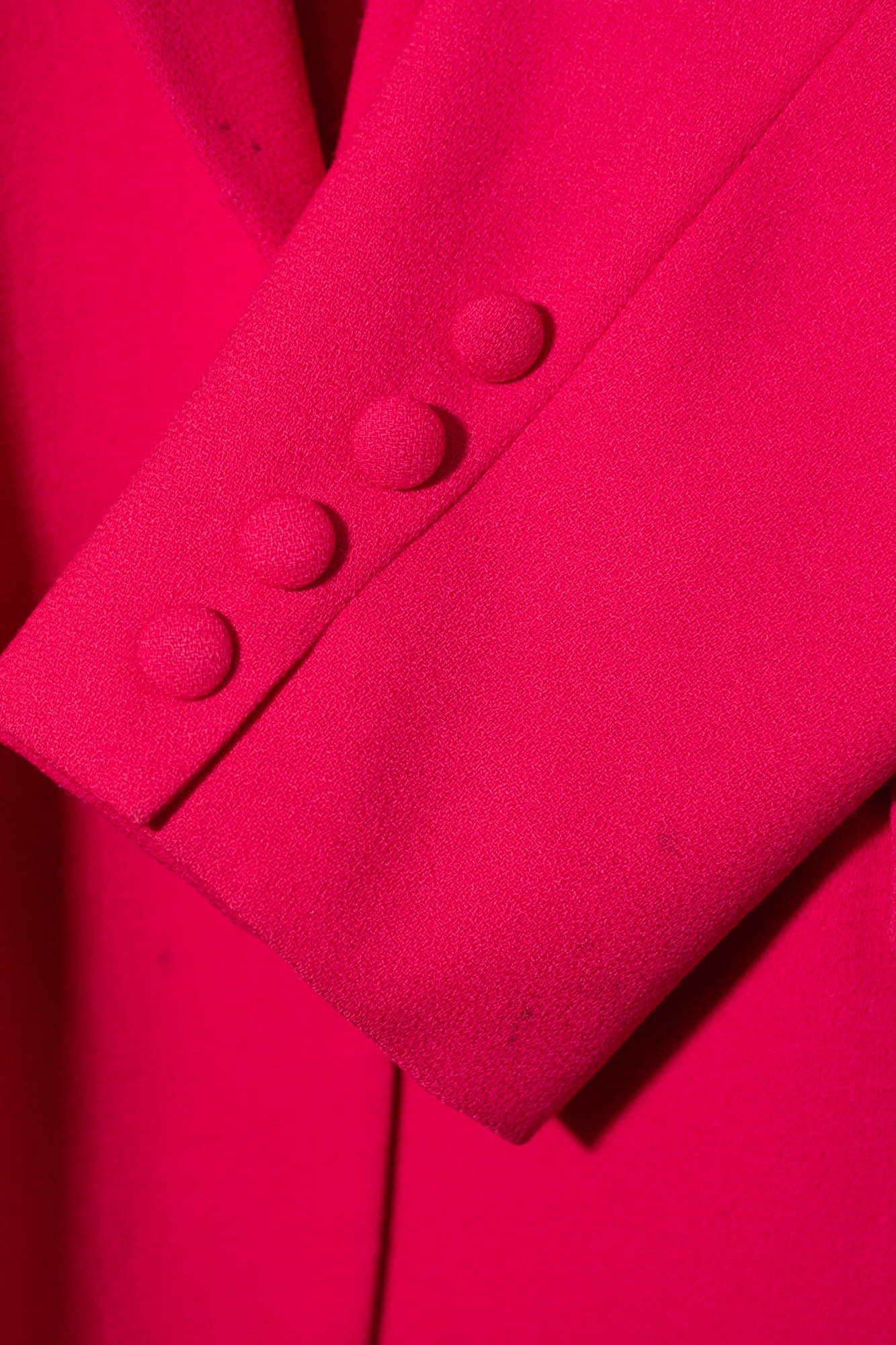 Close-up of a bright pink coat with buttons on a matching background