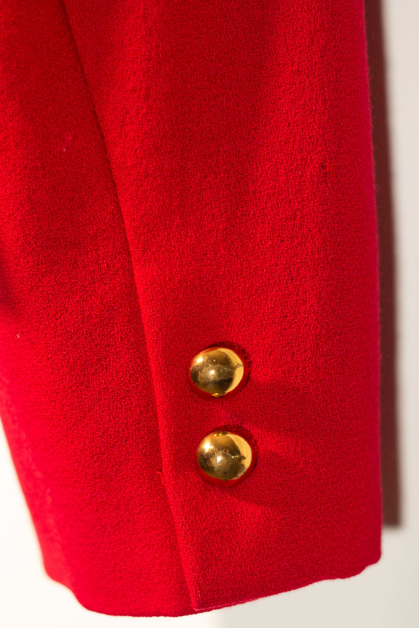 Close-up of a red coat with gold buttons on a white background
