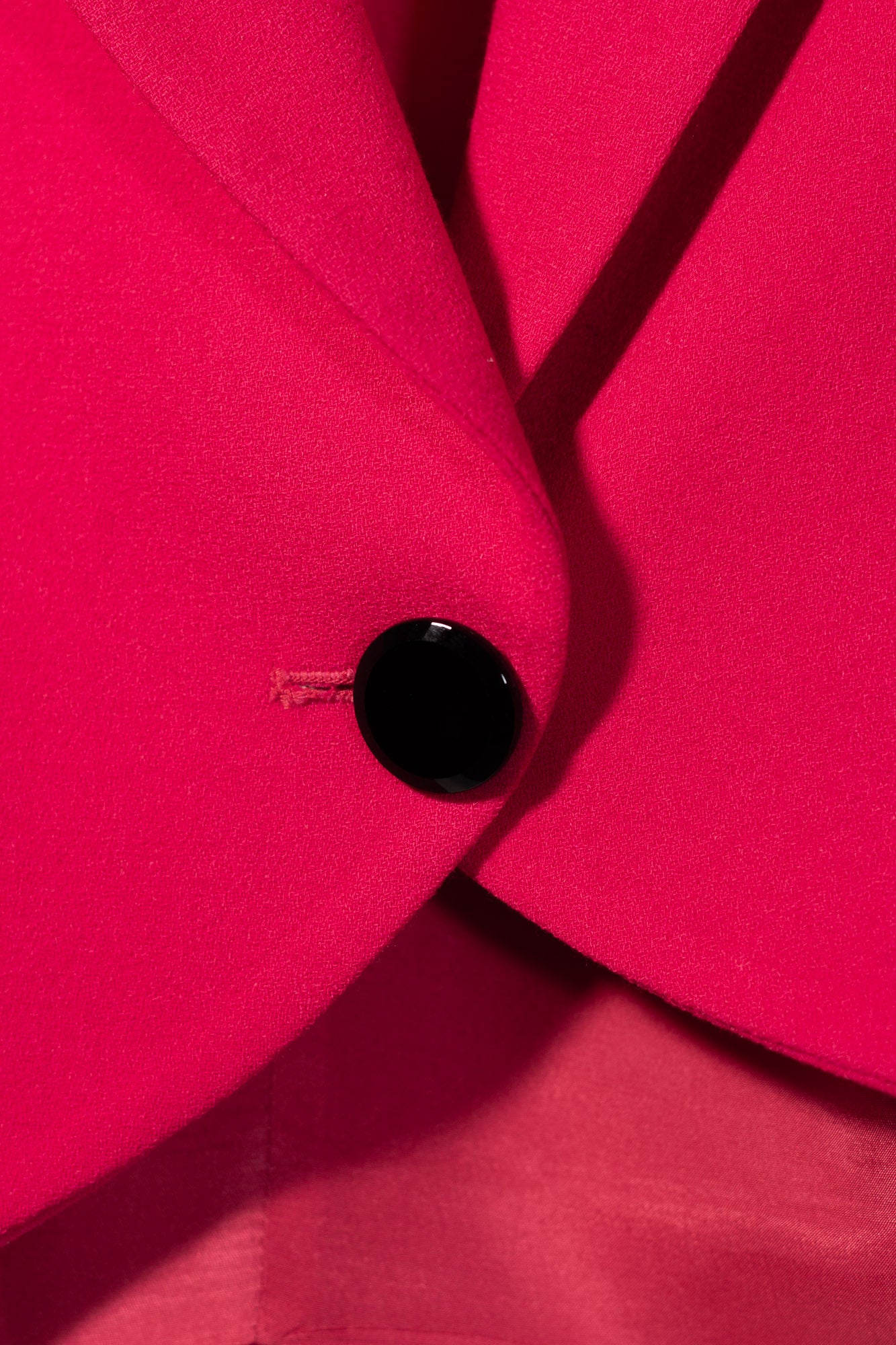 Close-up of a black button on a bright pink fabric background