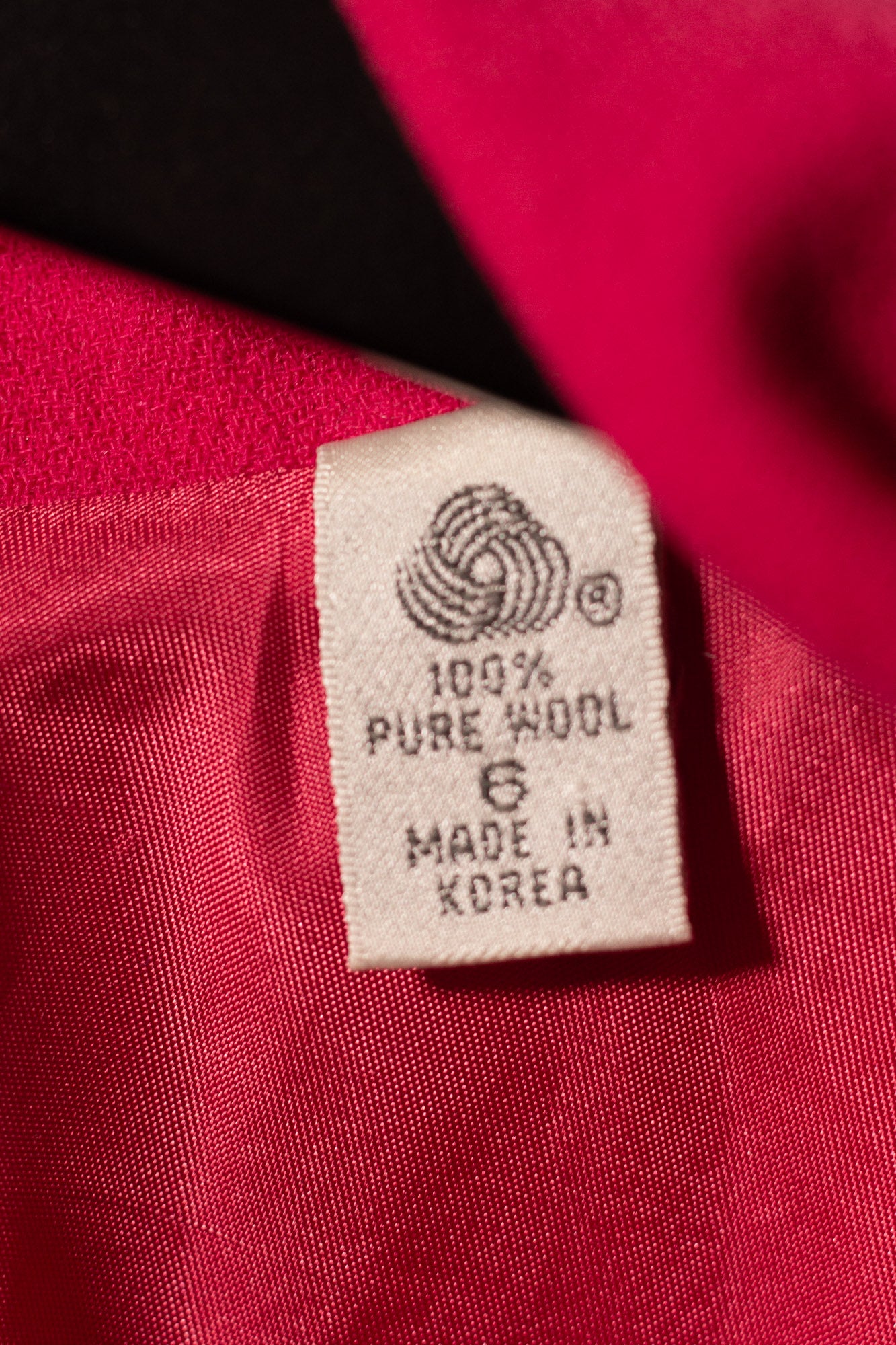 Label on red fabric indicating 100% pure wool and made in Korea