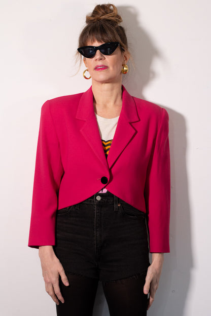 Person wearing a bright pink blazer against a white background