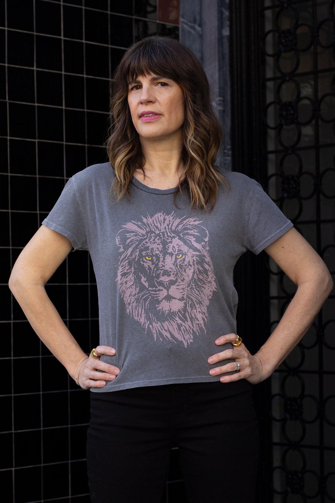 Woman wearing a black t-shirt with a lion graphic design against a dark background.