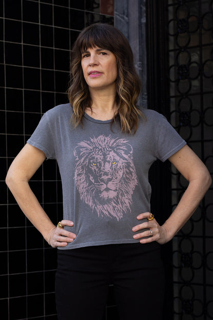 Woman wearing a black t-shirt with a lion graphic design against a dark background.