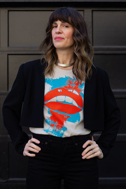 Woman wearing a graphic t-shirt with a colorful design in front of a dark background