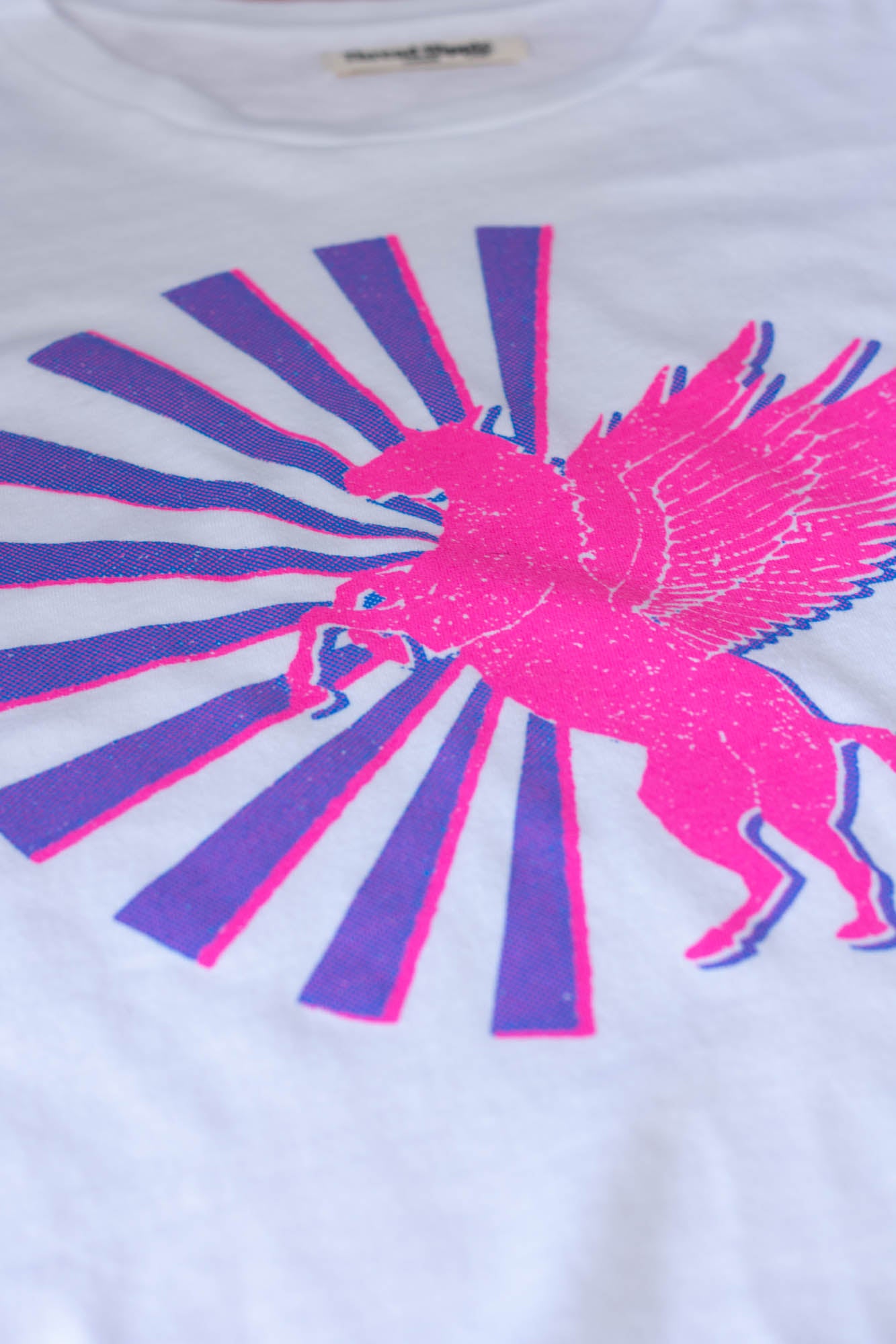 White t-shirt with pink and purple graphic design of a horse and sun rays.