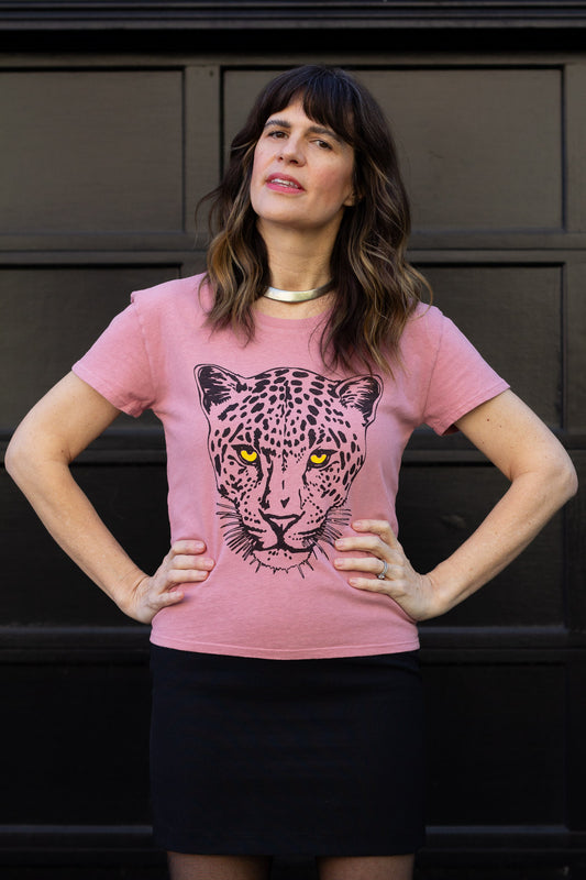 Woman wearing a pink t-shirt with a leopard graphic against a dark background.