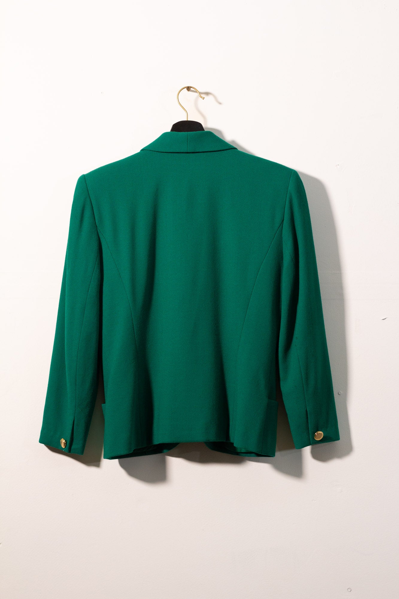 Green jacket on a hanger against a white background