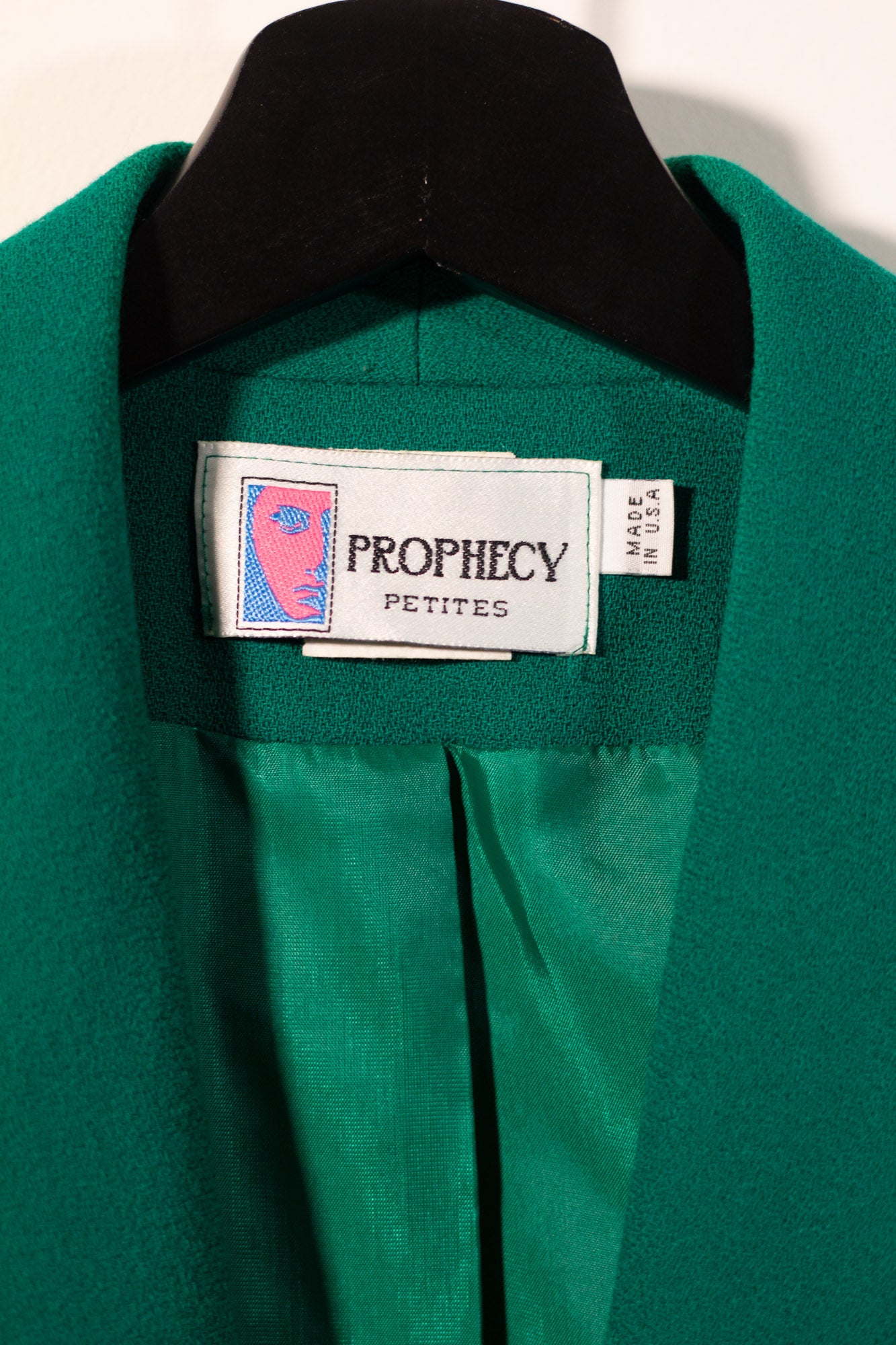 Green garment with 'Prophecy Petites' label on a beige background