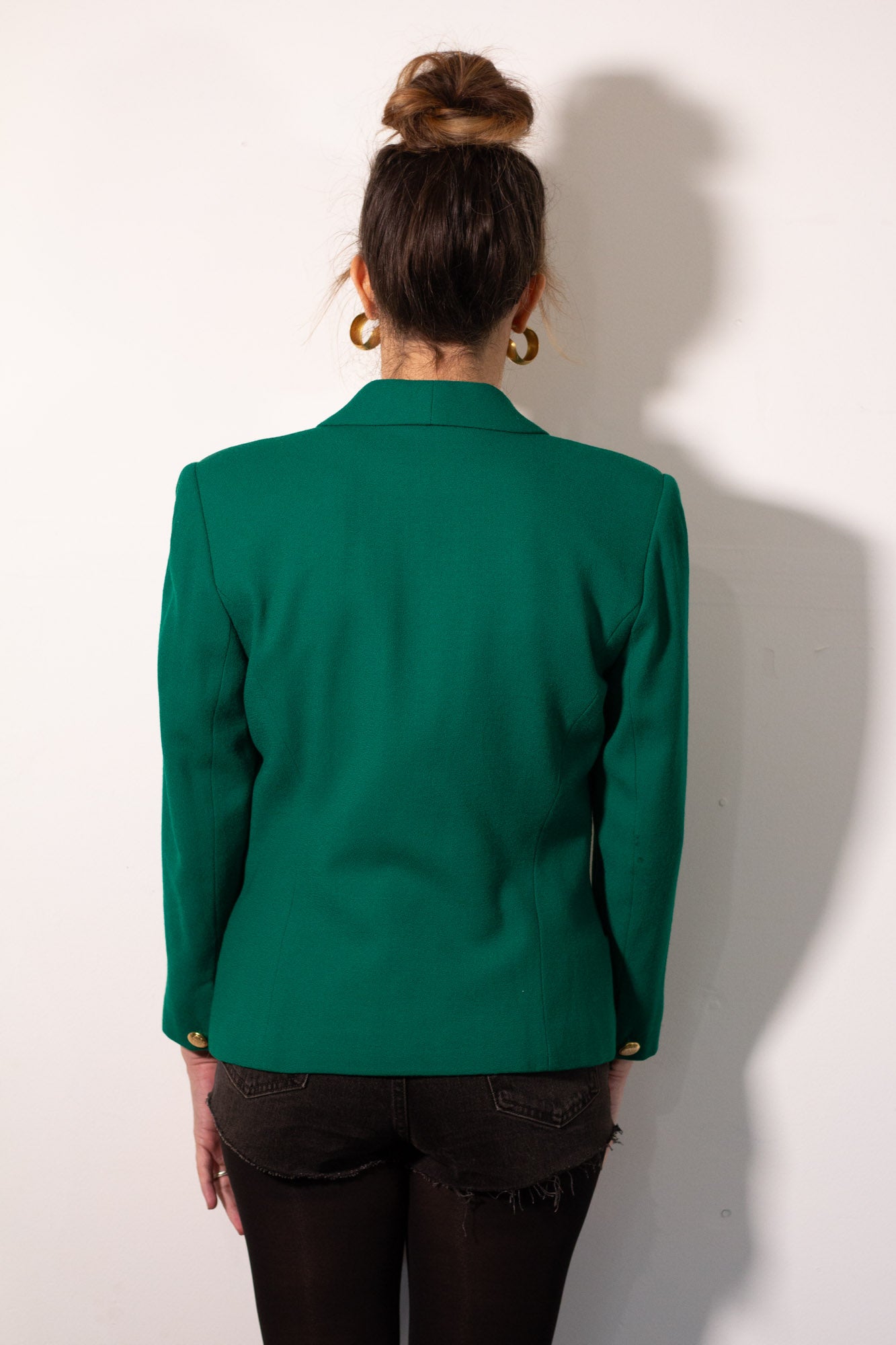 Person wearing a green blazer from behind on a white background